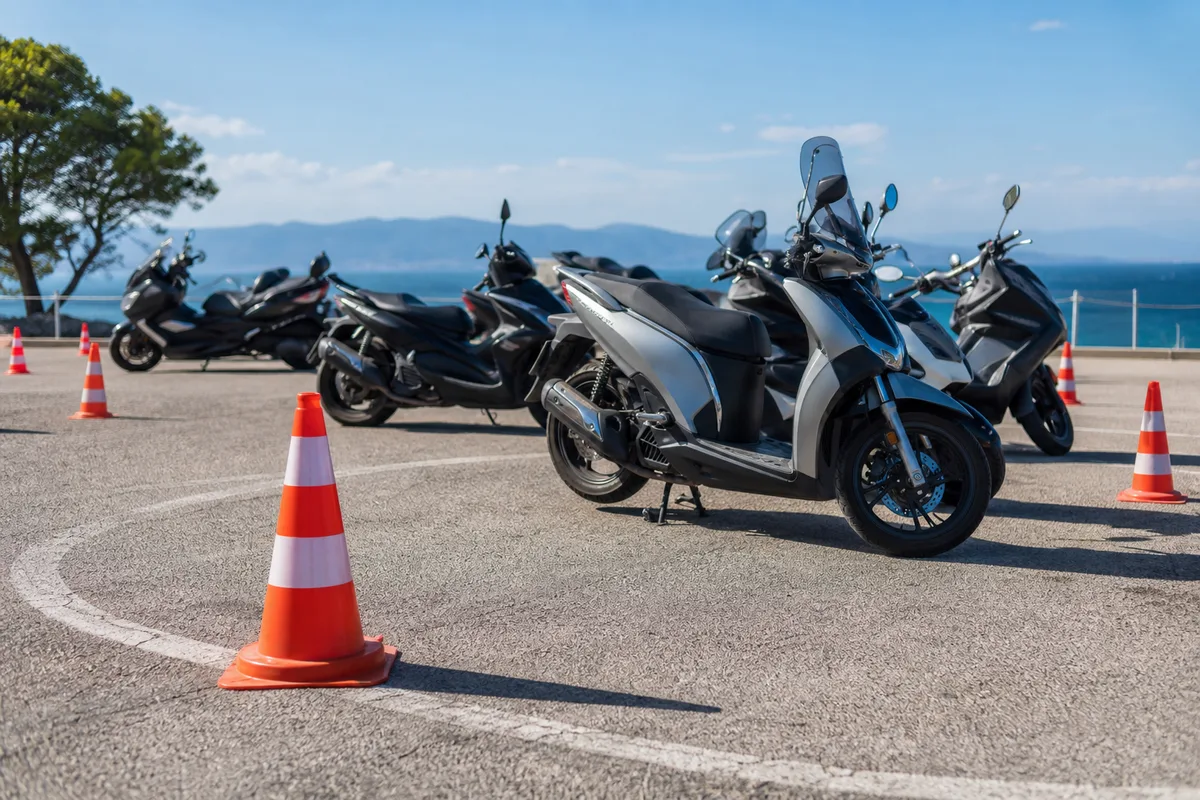 Groupe de scooters à l&rsquo;arrêt sur une aire de manoeuvre, cônes de signalisation au sol